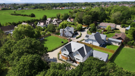 Aerial view of 2 The Paddocks, Burnham-on-Crouch, showing the house within its private close, the wooded copse alongside and open countryside beyond